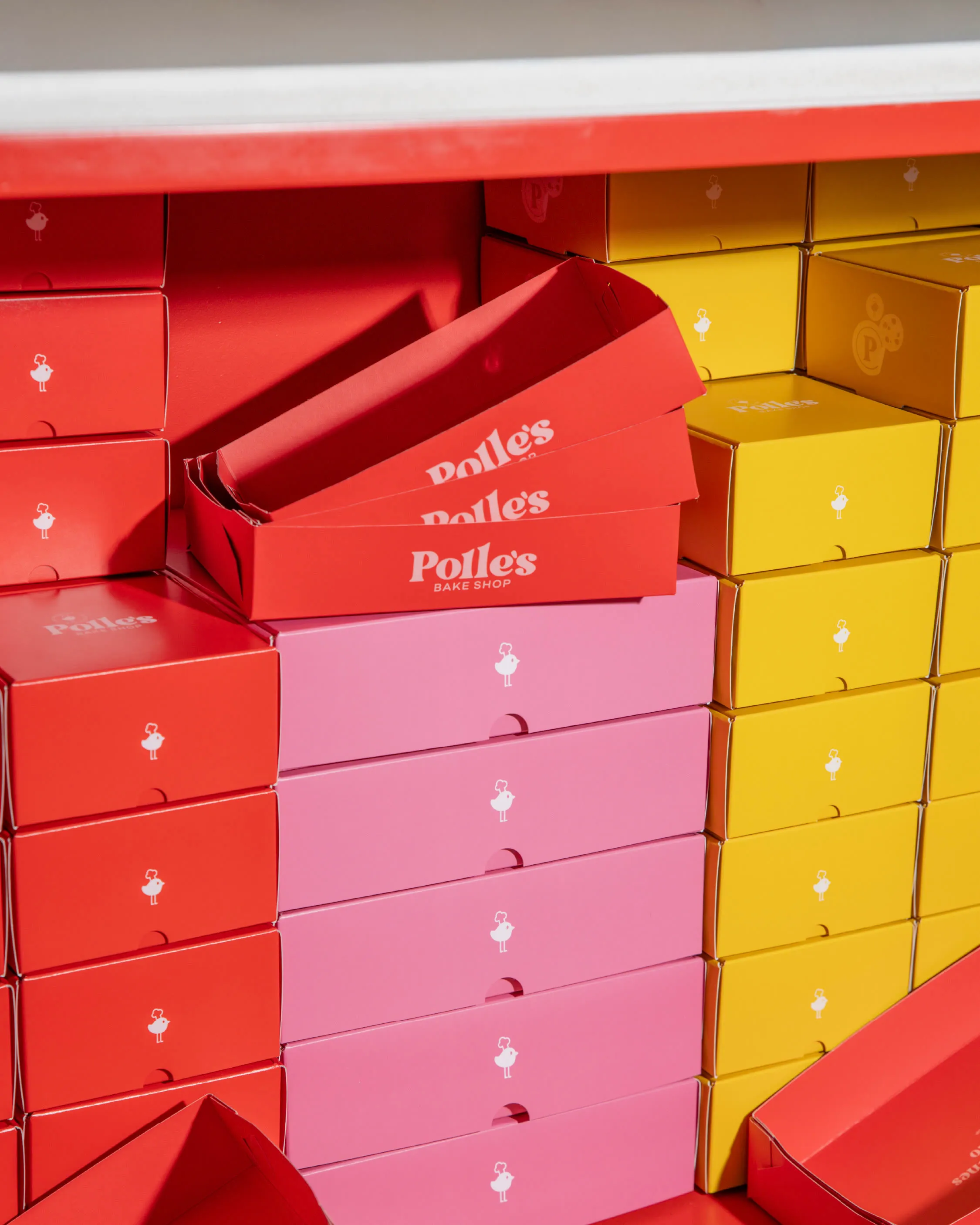 Cajas de galletas apiladas en rojo, rosa y amarillo con el logotipo de Polle’s